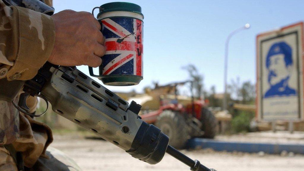 In this hand out image by the British Defence Ministry, a UK soldier serving with Number 1 Company 1st Battalion The Irish Guards, stands with his mug of tea after a successful raid on a large complex on the outskirts of Basra 3 April 2003