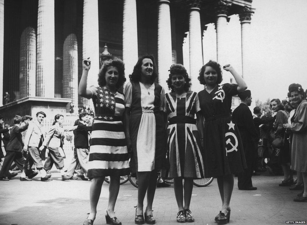 Women in dresses that look like the flags of the USA, France, Great Britain and the Soviet Union