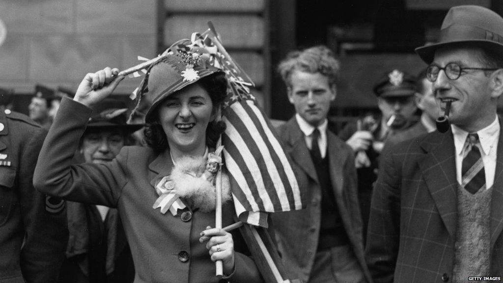 A woman holds an American flag over her head during VE day celebrations in Piccadilly Circus in London