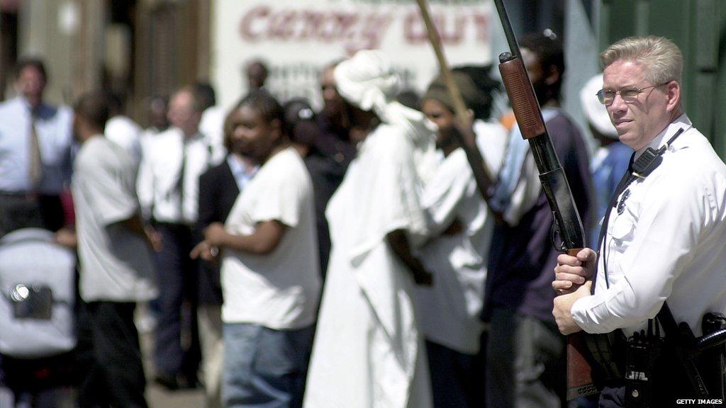 Cincinnati Police officer watches pedestrians April 13, 2001 in the Over the Rhine area of downtown Cincinnati, Ohio