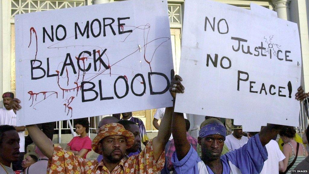 Daryl Hammond (L) and Terrell Bonner (R) display signs of protest outside of the New Friendship Baptist Church 12 April, 2001 in Cincinnati, OH,