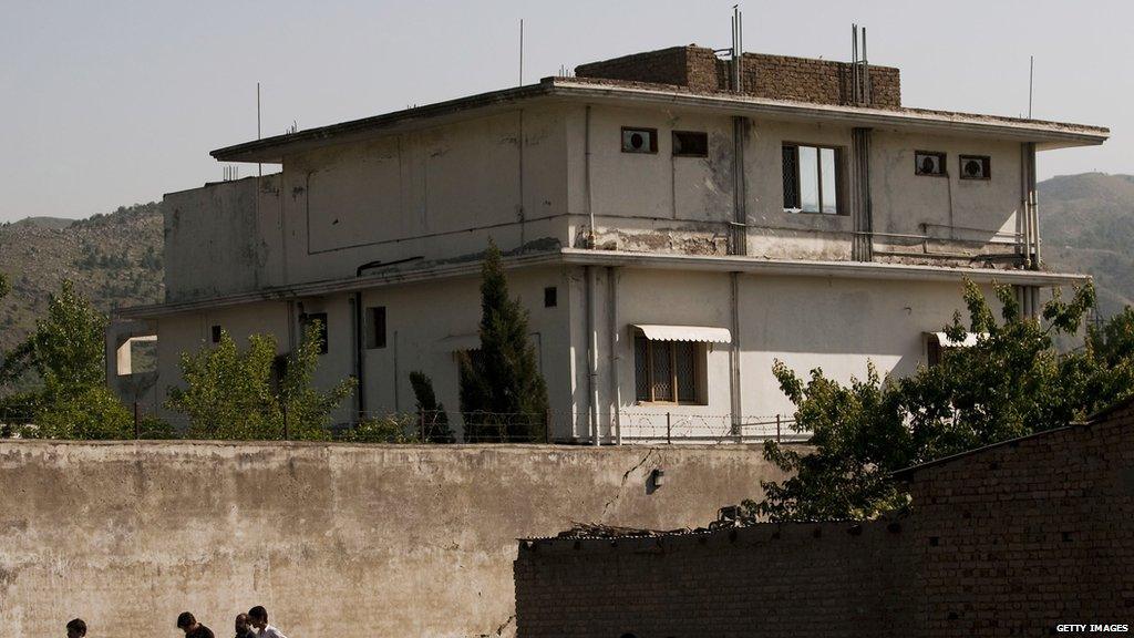 People walk past Osama Bin Laden's compound, where he was killed during a raid by U.S. special forces, May 3, 2011 in Abottabad