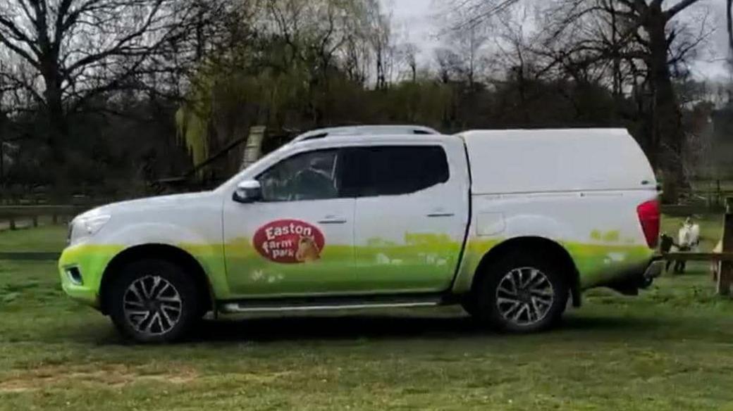 A white and green truck with an Easton Farm park logo printed on the side.