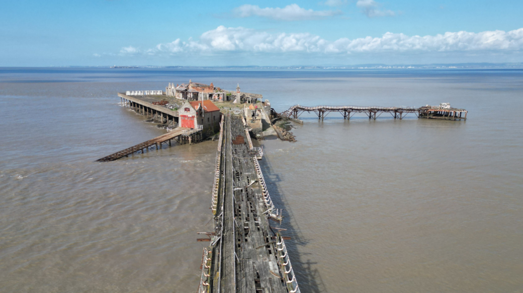 A wide shot showing the bridge and pier in poor, crumbling condition