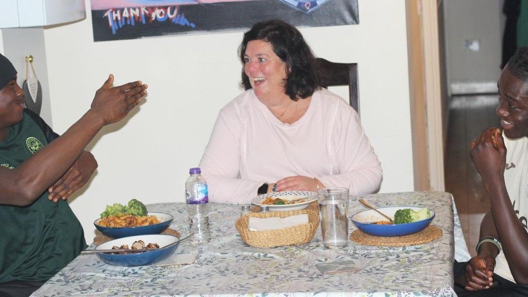 Young Brentford academy footballers laugh while eating a meal at home with their host family