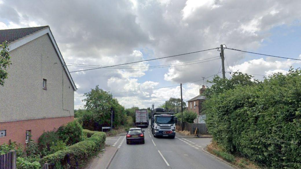 Two lorries and a car are seen near a junction with the single-track Kent Street