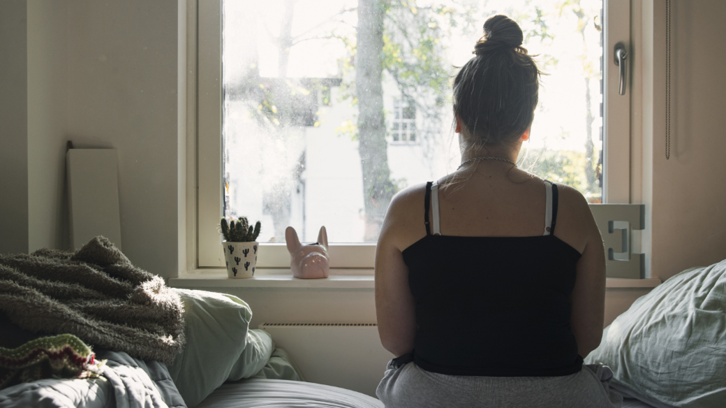 Child in care home with back turned to camera, looking out of a window