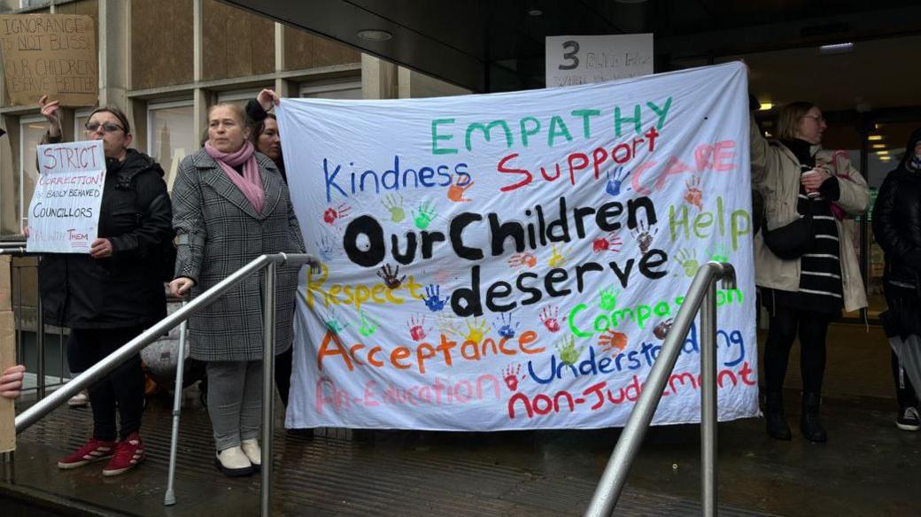 A group of women holding up signs during a protest outside Warwickshire County Council