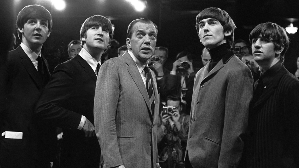 The Beatles and US TV presenter Ed Sullivan on the set of the Ed Sullivan Show looking off-camera.