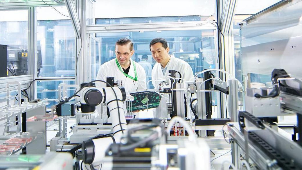 Alex Zhavoronkov and a colleague work with lab equipment