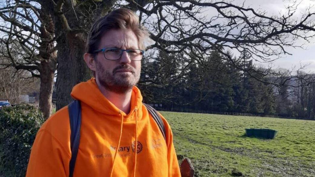 A man in glasses and an orange hoody