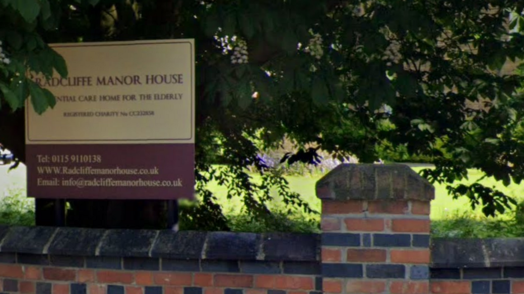 The sign for Radcliffe Manor House which is under a tree.