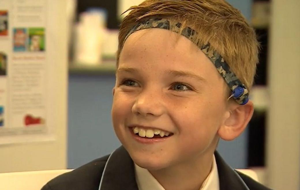 Boy smiling at camera with army headband and black blazer.