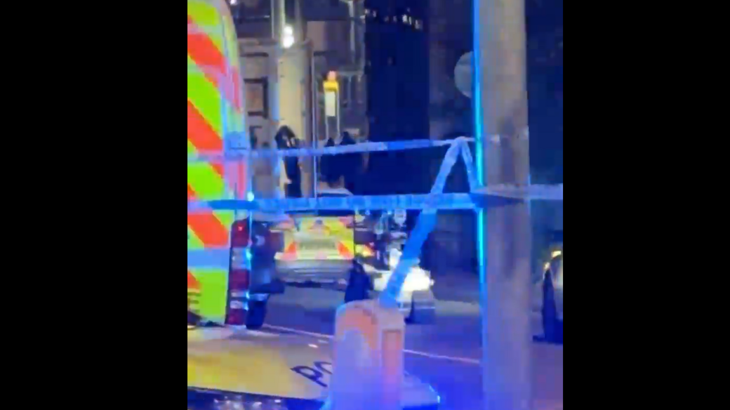 A bomb squad robot is seen moving towards a bus, alongside a police van in an area covered in police tape.