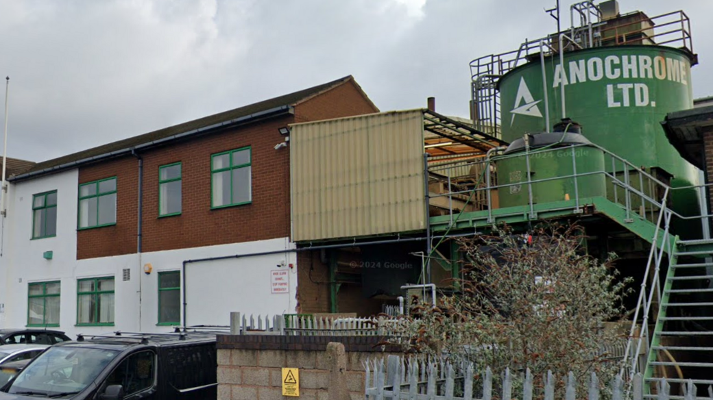 A two-storey white and brick building, with a large green storage tank to the right of the property, emblazoned with the words Anochrome Ltd