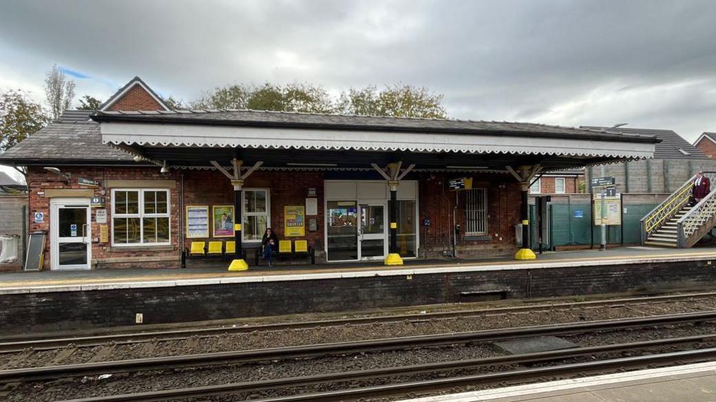 Maghull railway station. a scalloped trimmed cover overlooks the tracks. 