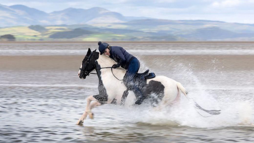 Rider lowers head to avoid spray from crossing through water