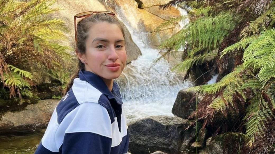 Shelby Smith posing in front of a stream waterfall