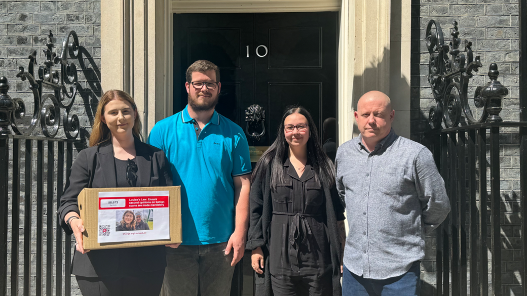 Chloe Hickman standing outside Number 10 Downing Street holding a cardboard box with a picture of her and her mum on it. She is standing next to her fiancé in a blue top, her best friend, who is wearing all black, and her dad, who is wearing a grey shirt. They are all looking into the camera.