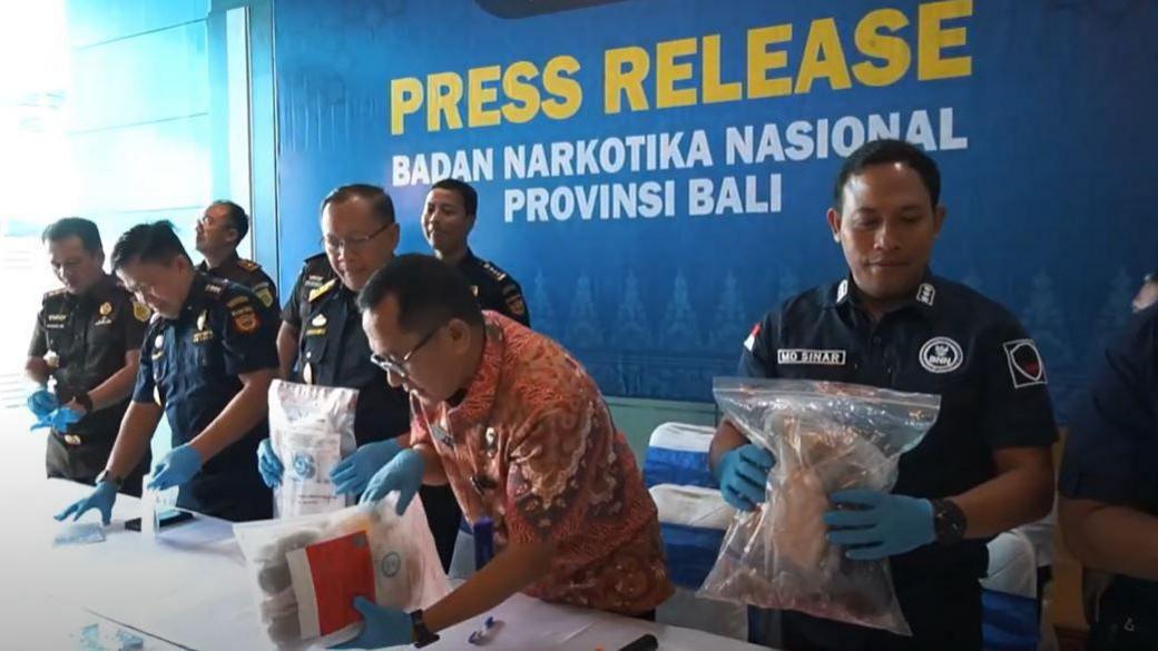 A line of men in uniform holding evidence bags said to contain drugs