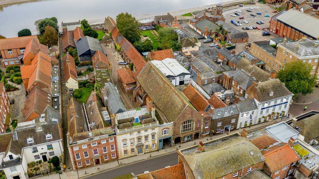 Aerial view of the guildhall. It sits on a street, surrounded by other buildings, but it noticeably longer than those around it. 