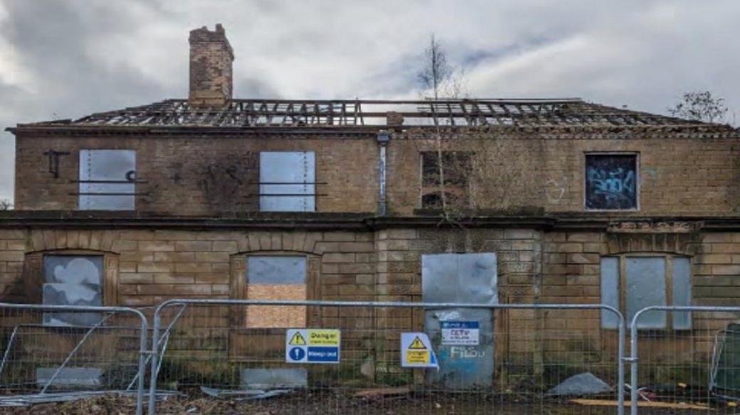 A derelict house behind metal fencing