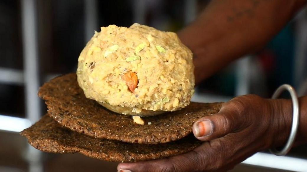 A hand holds up a famous Tirupati laddu