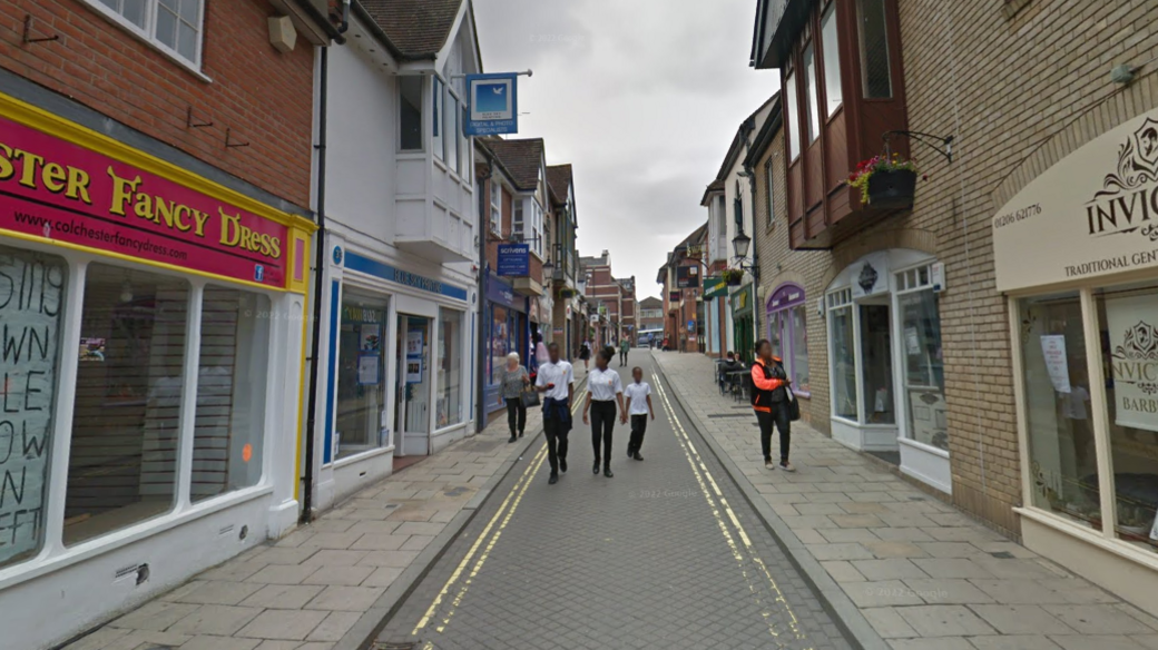 Google image of Sir Isaacs Walk in Colchester. There are shops on the side and people are walking on a narrow road.