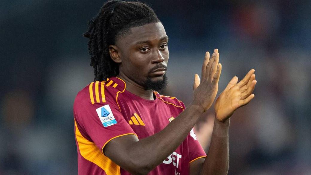 Manu Kone applauds supporters, he is wearing Roma's home red burgundy shirt