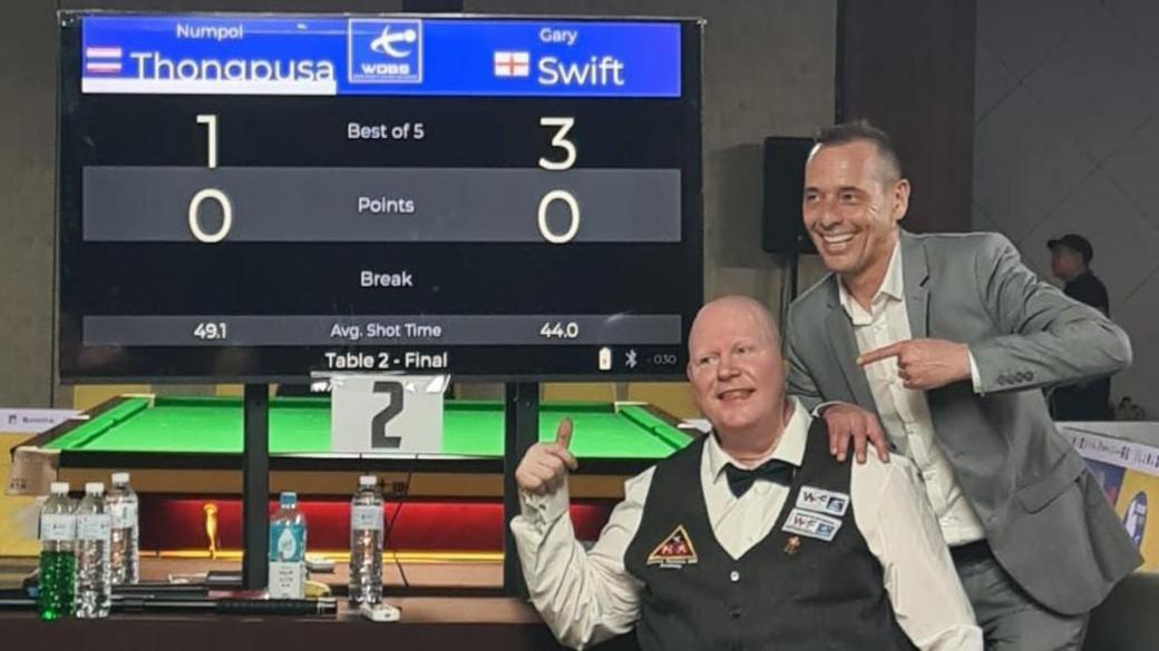 Gary pointing to the scoreboard for the championship final, showing his 3-1 victory in the best-of-five game.