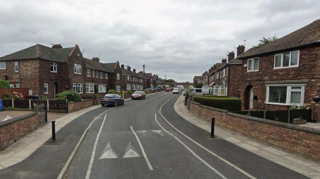Google streetview of houses on both sides of road and parked cars on pavements.