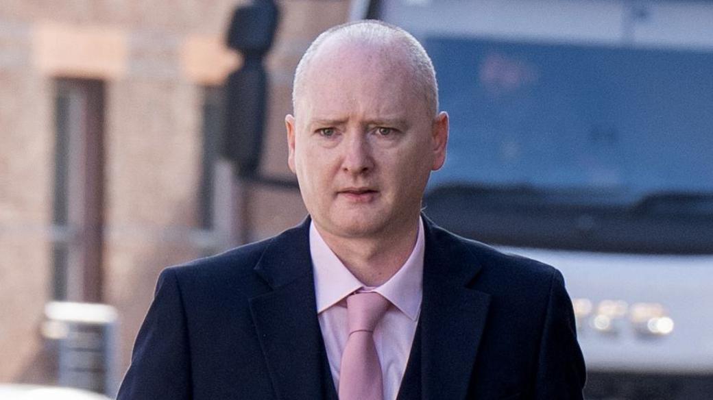 Graeme Dott arriving at the High Court in Glasgow. He is wearing a dark suit over a pink shirt witha pink tie.
