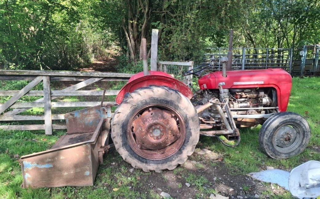  A red tractor left by a wooden gate 