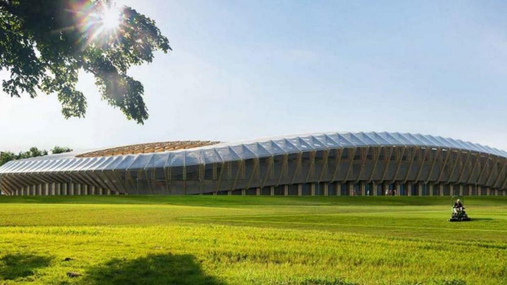 An artist's impression of the new stadium in an ergonomic design with green grass outside and a man on a lawn mower