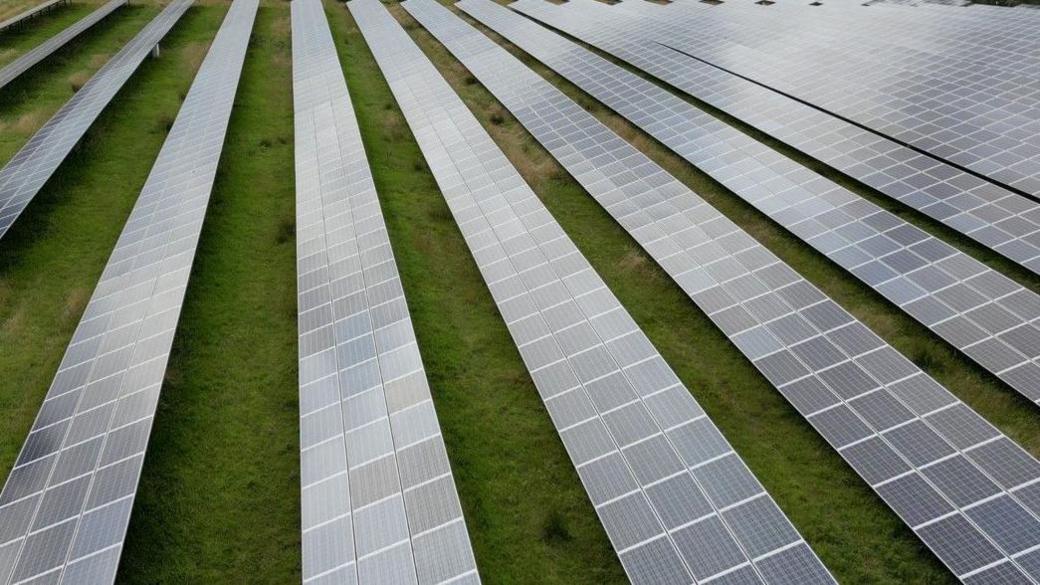 A large rural field filled with rows of solar panels