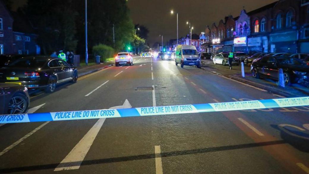 Police tape covers Dickenson Road in Longsight on Monday evening.