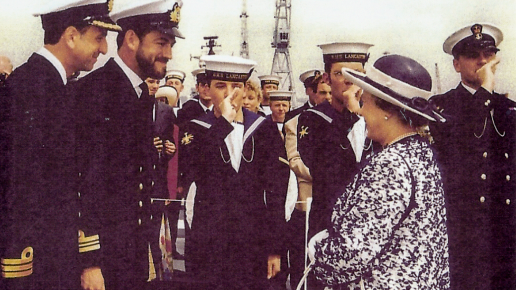 Commander Woods and other personnel onboard HMS Lancaster welcoming Queen Elizabeth II in 1997. They are all smiling at each other