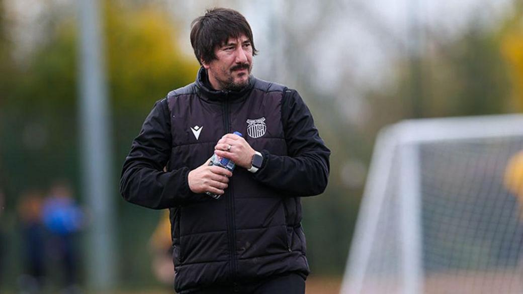 Jason Land, on a football pitch, wearing a black Grimsby Town body warmer, carrying a bottle of water