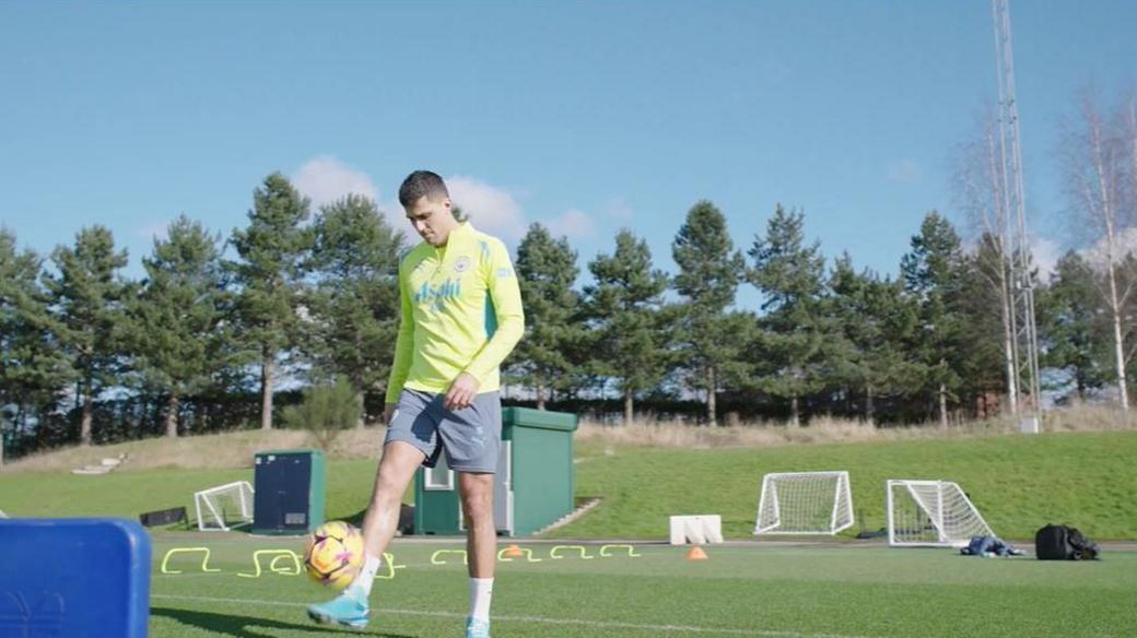 Rodri in training kit, kicking a football