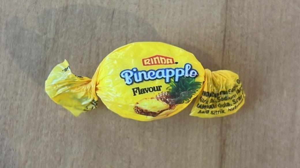 A sweet wrapped in Rinda brand pineapple flavour sweet paper