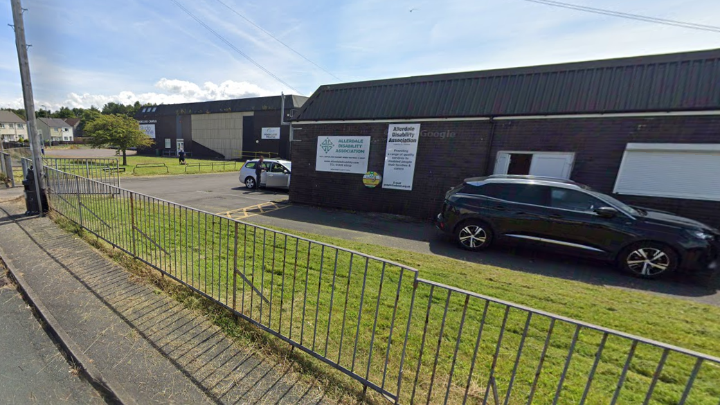 Allerdale Disability Association, a brick building with a lawn in front. Cars are parked outside.