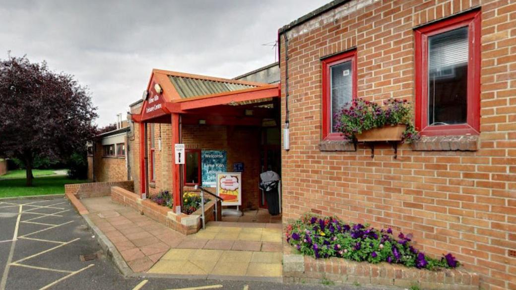 Red brick front entrance to the leisure centre with some flowers planted outside