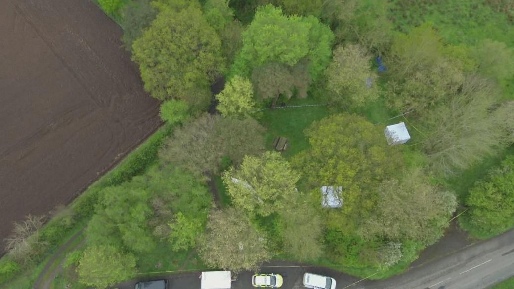 An aerial view of the woods where Paul Taylor's body was found. There is police tape and tents.