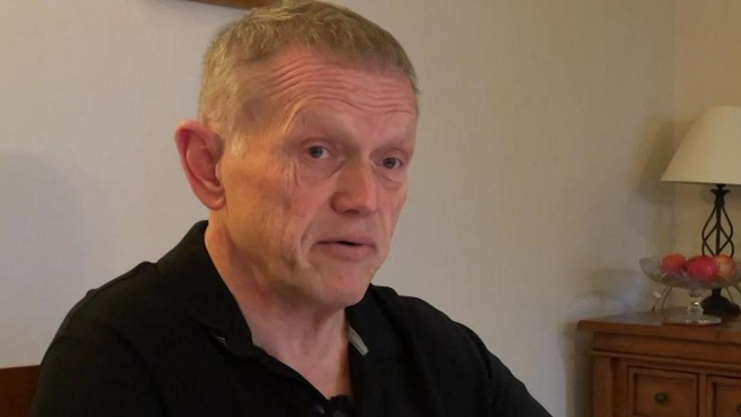 Richard Barker sitting at his dining room table looking over paperwork to do with his investment in Arndale House in Liverpool. 