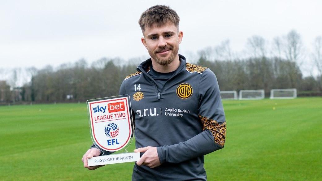Ben Knight wearing Cambridge United training kit holding his League Two player of the month award