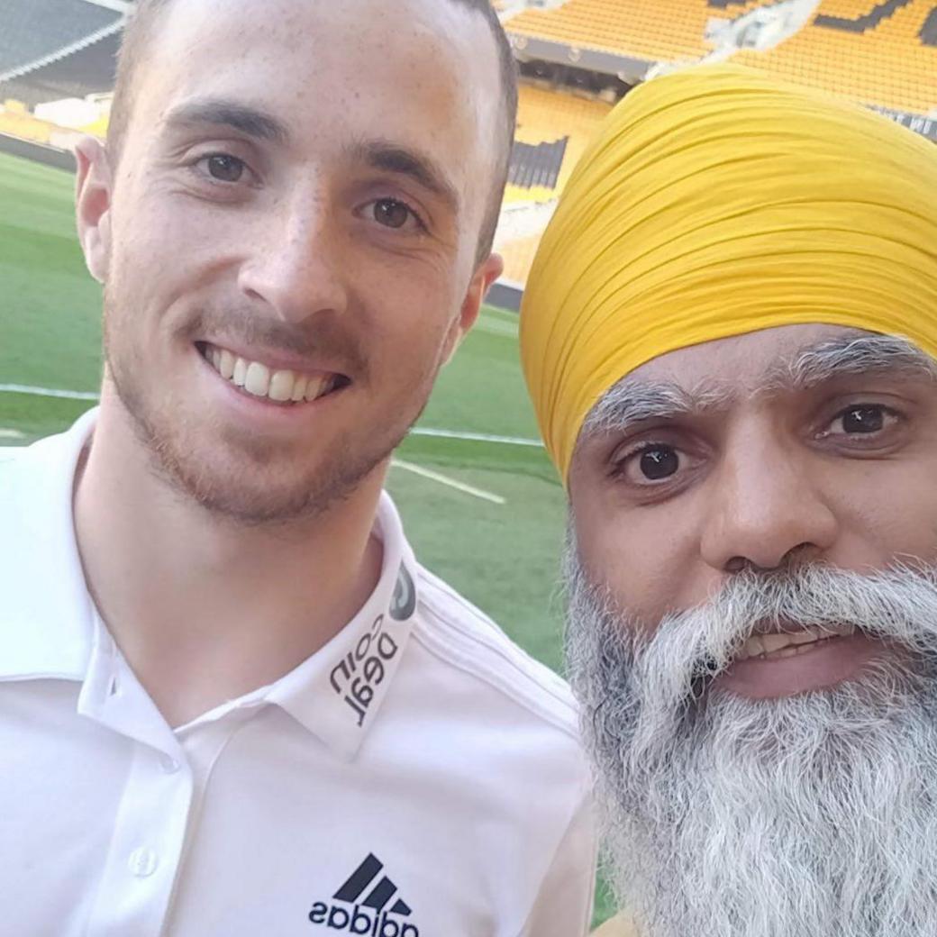 Jota stands on the left in a white Addidas shirt next to Wolverhampton fundraiser Manny Singh - who is wearing a yellow turban and shirt. He has a long white beard.