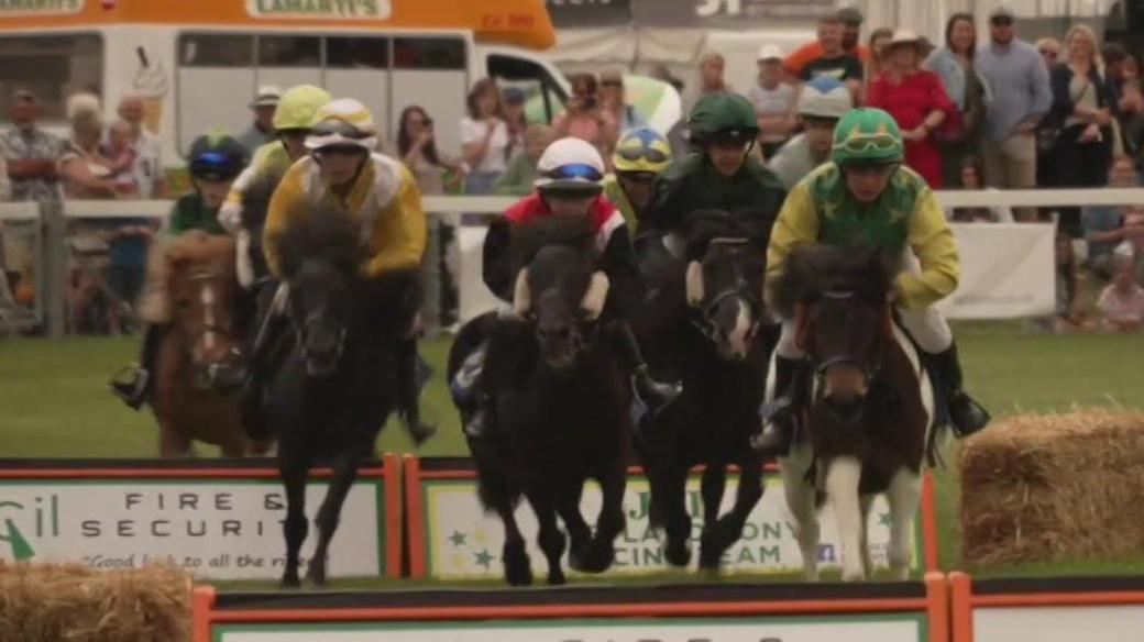 A series of people on ponies racing in a race. 