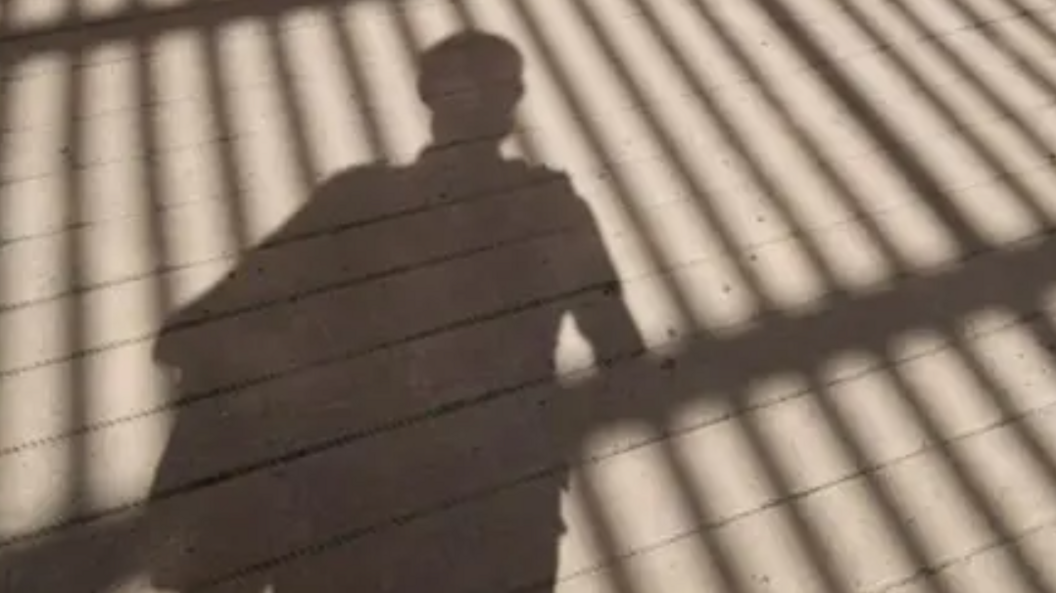 A stock image of a child's shadow in front of gates.