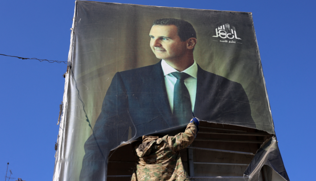 A rebel fighter tears down a portrait of Syria's President Bashar al-Assad in Aleppo, after it was captured by Hayat Tahrir al-Sham and its allies on 30 November 2024