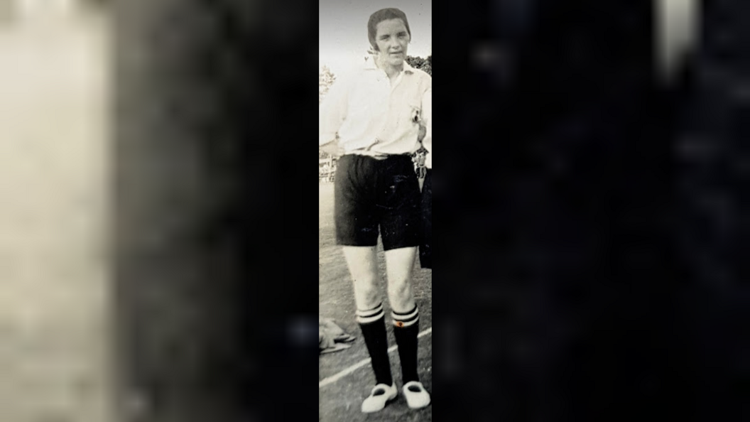 A black and white picture of a woman in a football kit.